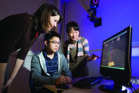 photo of 3 people looking at a computer screen