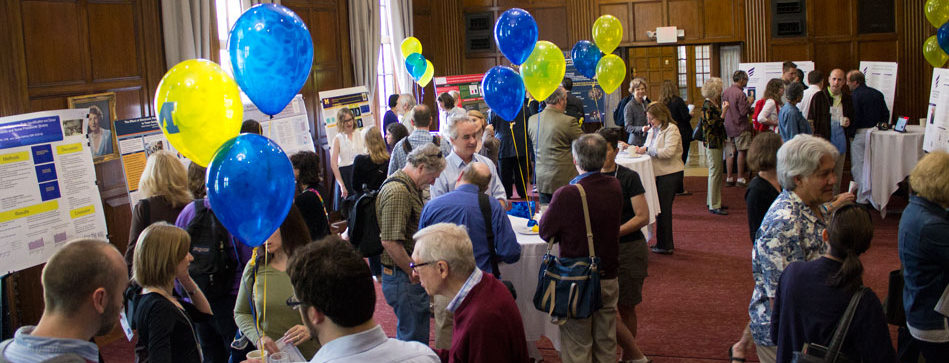Poster fair with lots of people, blue and yellow balloons decorate the room