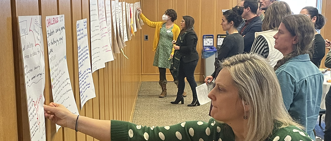 A group of people reading poster papers on a wall