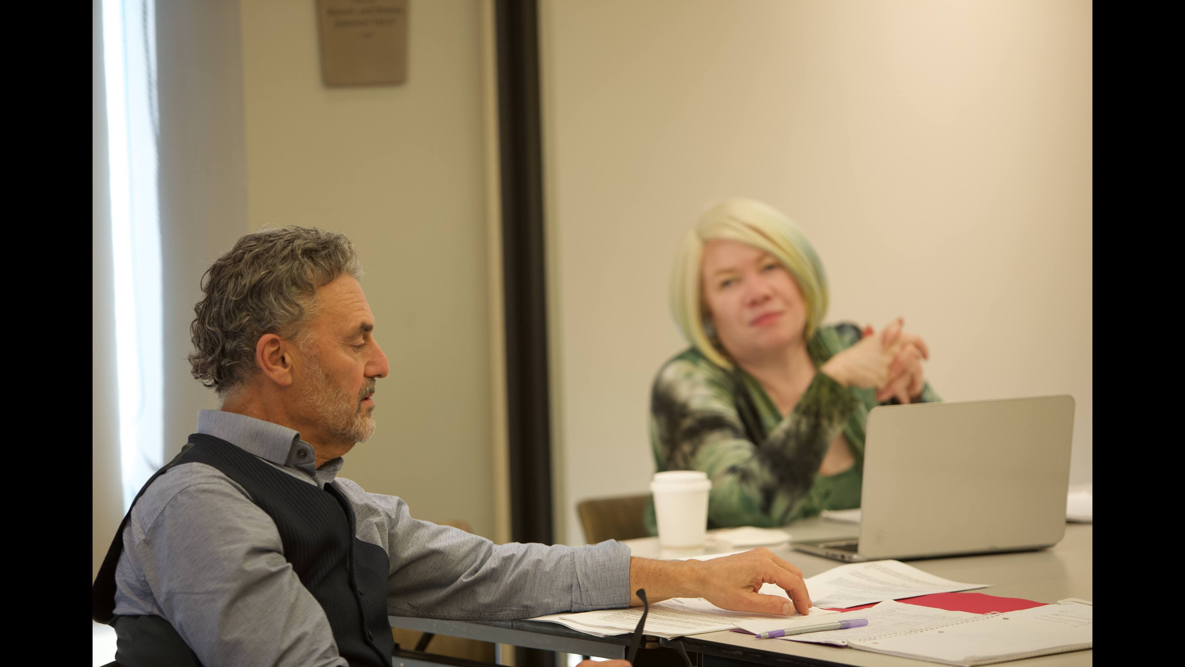Two actors seating in a conference room