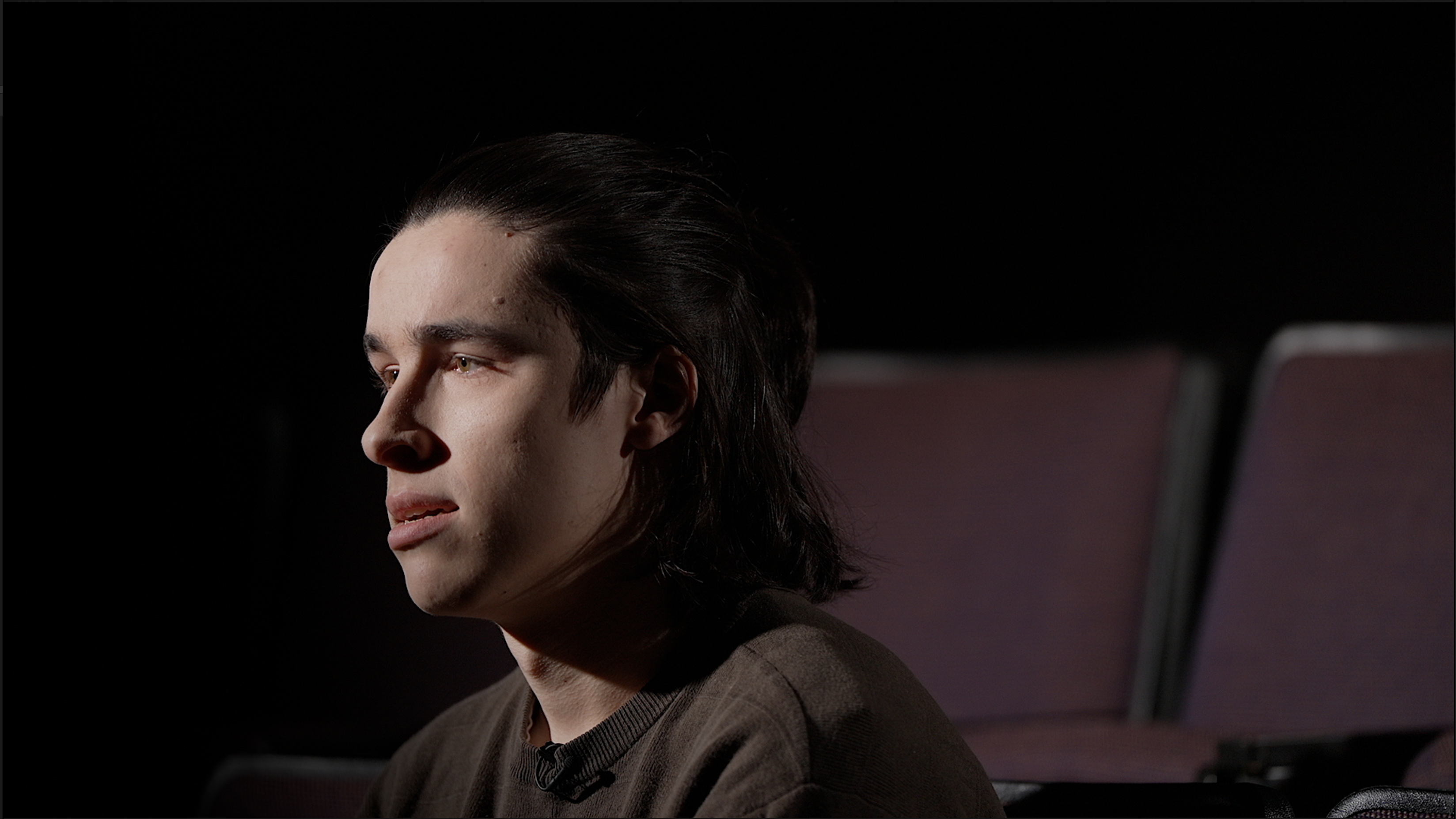 Actor in side profile seating in an auditorium