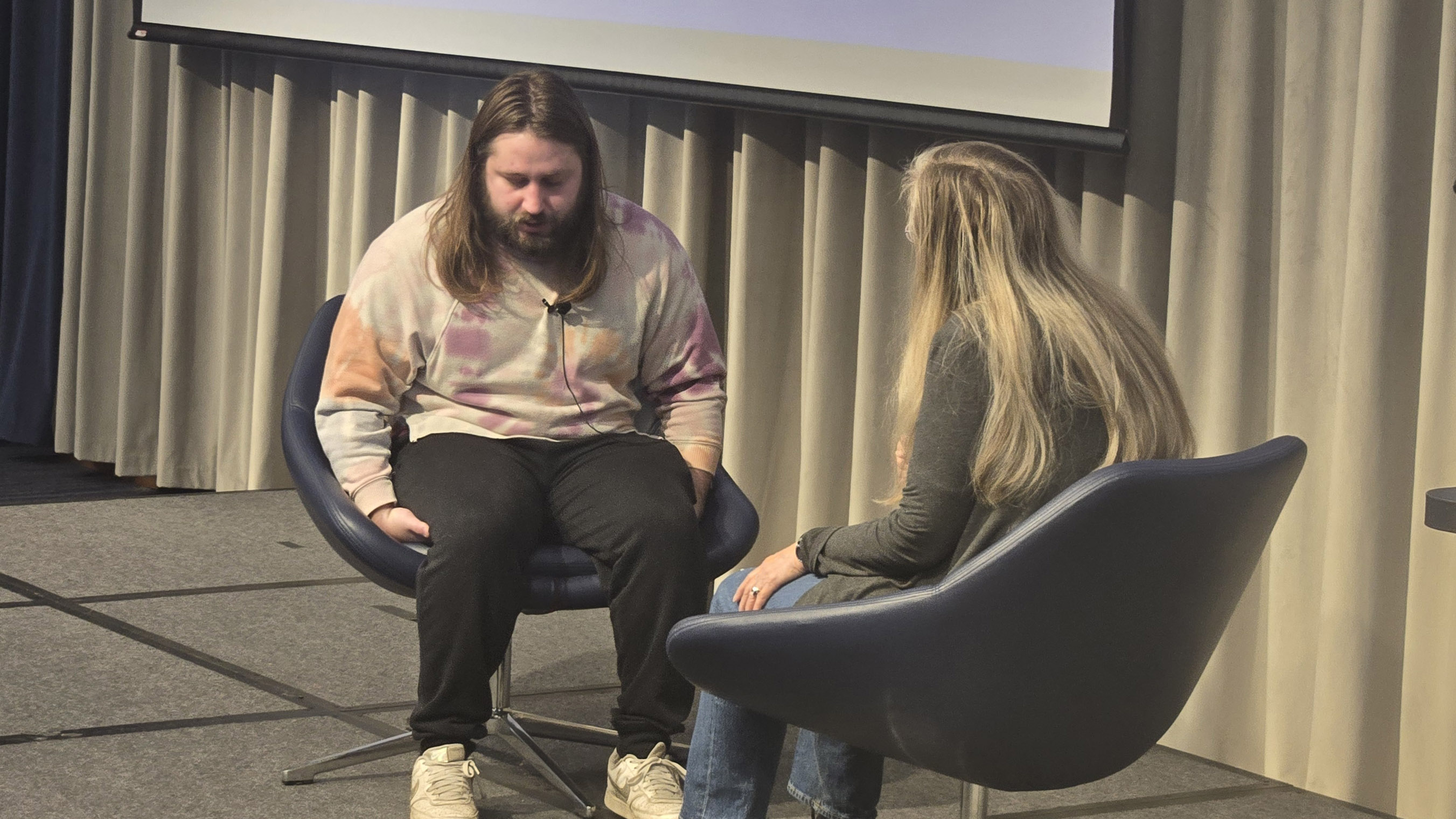 Two actors seating across each other on a stage